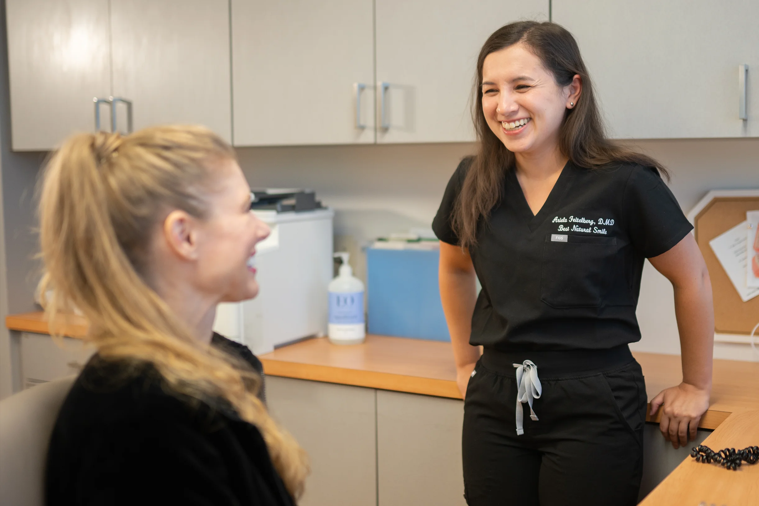 Smiling dentist talking with a staff member inside Best Natural Smile