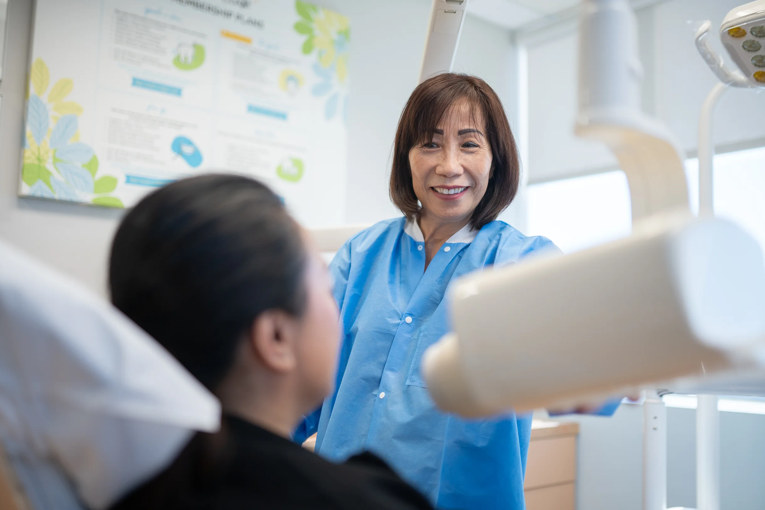 Dental team member positioning dental equipment while assisting a patient at Best Natural Smile
